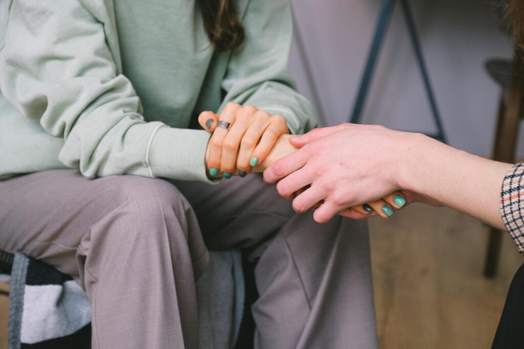 pexels-photo-7176325-7176325 Close-up of two people holding hands during a comforting therapy session.
