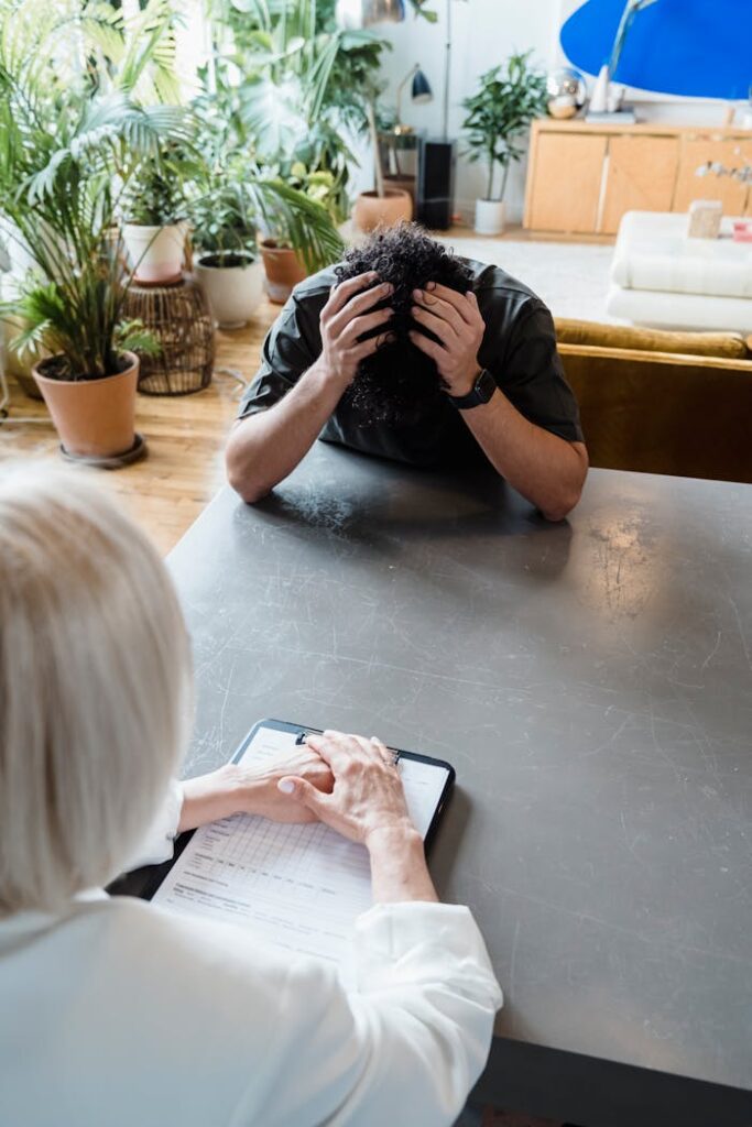 pexels-photo-8560048 A therapist consults a distressed man in an indoor psychotherapy session.